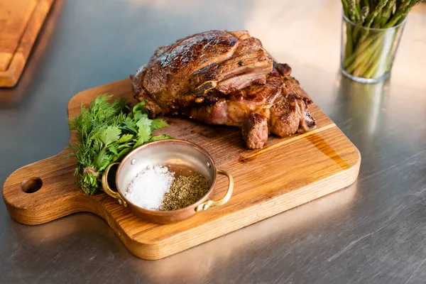 Vista de ángulo alto de las especias cerca de la carne cocida y verduras en la tabla de cortar en la cocina - foto de stock