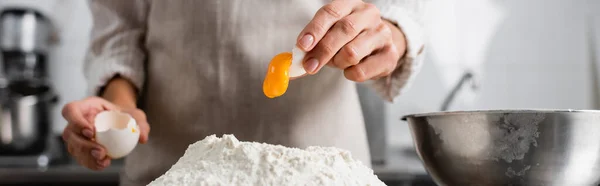 Vista recortada del chef vertiendo la yema de huevo en la harina en la cocina, pancarta - foto de stock