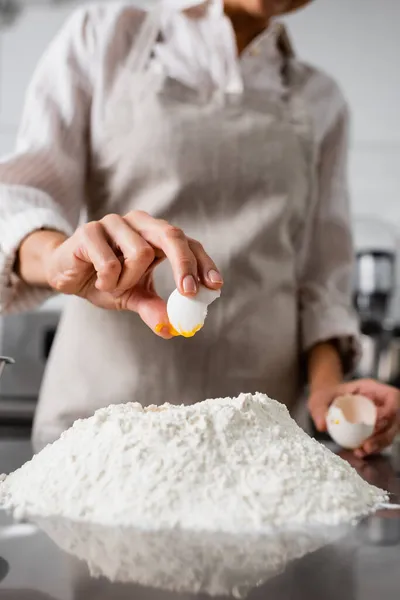 Ausgeschnittene Ansicht des Chefs, der Ei auf Mehl auf Küchentisch gießt — Stockfoto