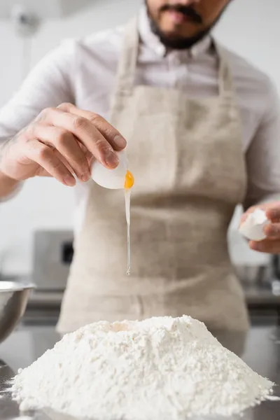 Ausgeschnittene Ansicht des Chefs, der in der Restaurantküche Ei auf Mehl gießt — Stockfoto