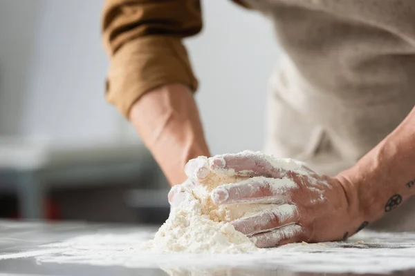 Cropped view of blurred chef making dough on kitchen table — Stock Photo