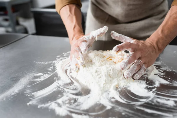 Cropped view of mature chef in apron making dough on kitchen table — Stock Photo