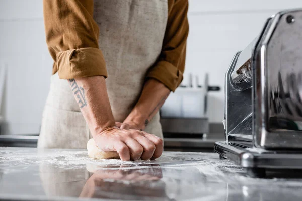 Cropped view of chef making dough near pasta maker machine on table in kitchen — Stock Photo