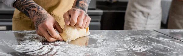 Vista ritagliata dello chef tatuato che fa pasta vicino alla farina sul tavolo della cucina, banner — Foto stock