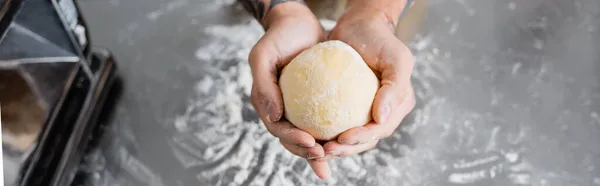Ausgeschnittene Ansicht des Chefs, der Teig in der Nähe einer verschwommenen Nudelmaschine hält, Banner — Stockfoto
