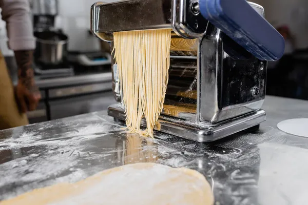 Cropped view of pasta maker machine with spaghetti in kitchen — Stock Photo