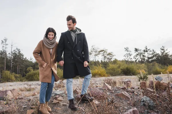 Young couple in autumn outfit holding hands while walking outdoors — Stock Photo