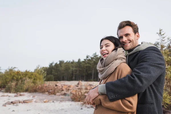 Pareja alegre en ropa de otoño mirando hacia otro lado mientras camina al aire libre - foto de stock