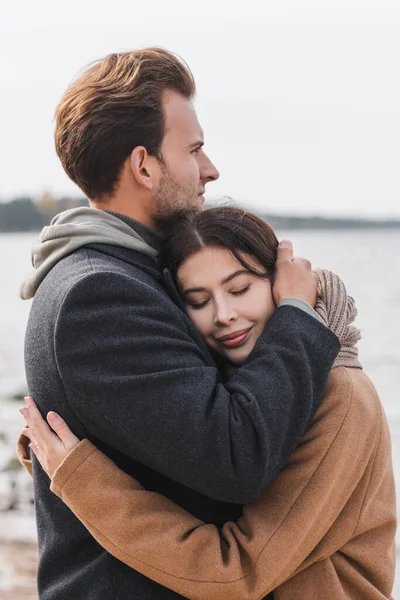 Happy woman with closed eyes hugging boyfriend during autumn walk — Stock Photo