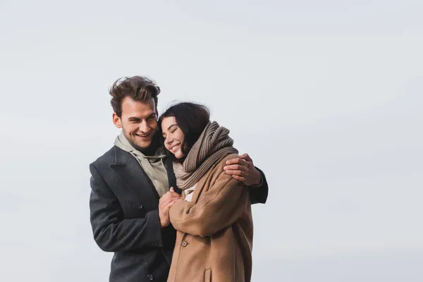 Feliz pareja en ropa de otoño abrazándose contra el cielo azul - foto de stock