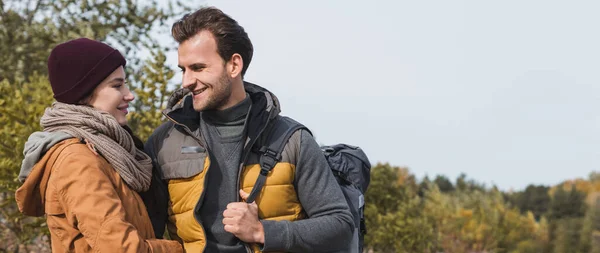 Happy couple in autumn clothes looking at each other while walking outdoors, banner — Stock Photo