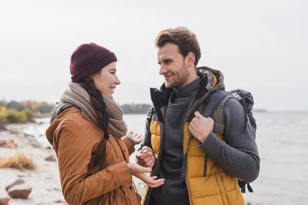 Young woman gesturing while talking to smiling boyfriend while walking outdoors — Stock Photo