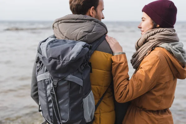 Jeune femme touchant épaule de l'homme avec sac à dos tout en marchant à l'extérieur — Photo de stock