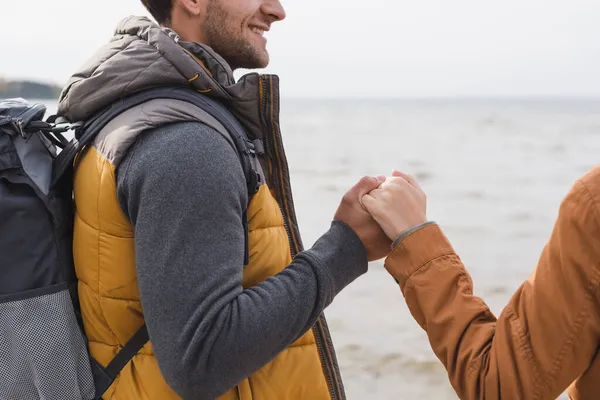 Vue recadrée du couple tenant la main tout en marchant près du lac — Photo de stock