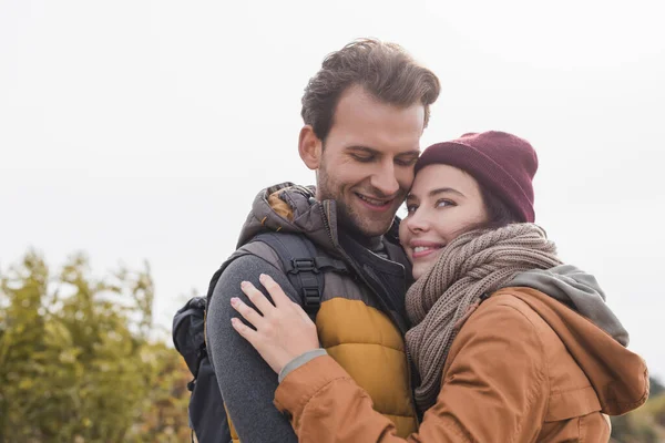 Happy young hikers in autumn outfit embracing while walking outdoors — Stock Photo