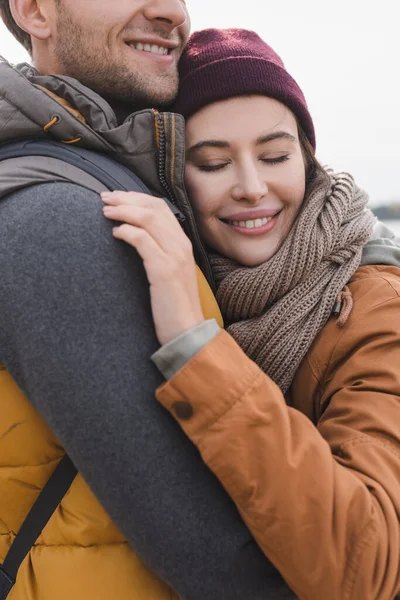 Happy woman in autumn clothes hugging man while walking outdoors — Stock Photo