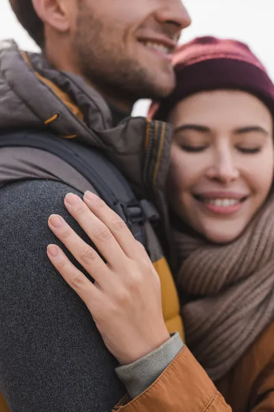 Mujer borrosa y alegre con los ojos cerrados abrazando novio mientras camina al aire libre - foto de stock