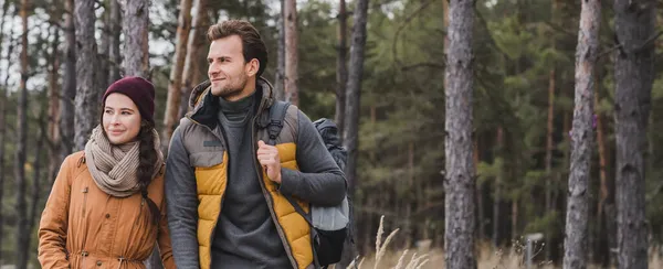 Young woman walking in forest near man wth backpack, banner — Stock Photo