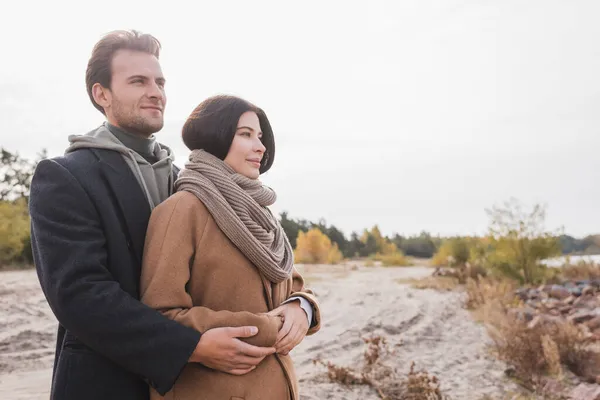 Junges und glückliches Paar in Mänteln schaut beim Herbstspaziergang weg — Stockfoto