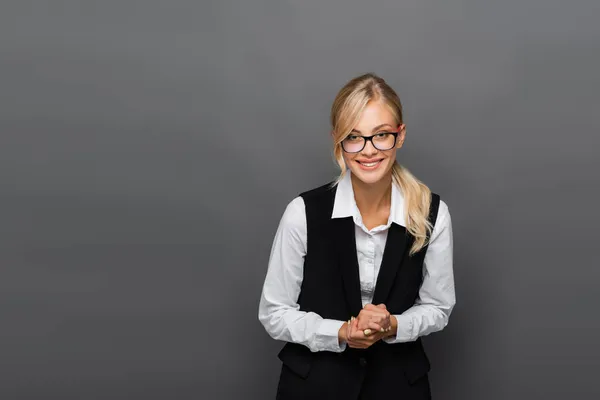 Donna d'affari positiva negli occhiali guardando la fotocamera isolata su grigio — Foto stock