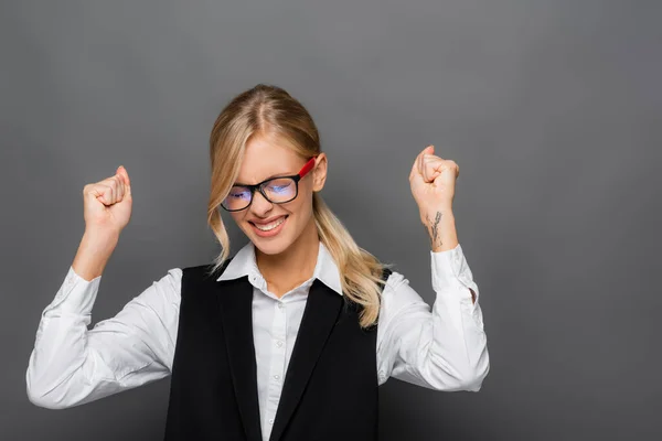 Emocionada mujer de negocios rubia mostrando sí gesto sobre fondo gris - foto de stock