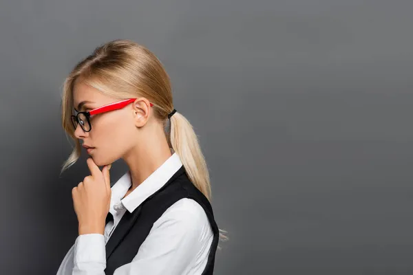 Vista lateral de la joven empresaria en gafas de pie aislada en gris - foto de stock