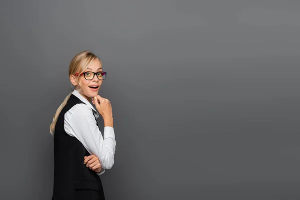 Astonished businesswoman in eyeglasses looking at camera isolated on grey — Stock Photo