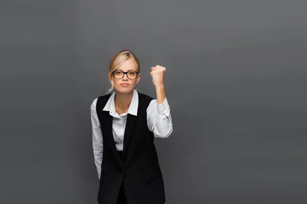 Empresária irritada em camisa e óculos mostrando punho isolado em cinza — Fotografia de Stock