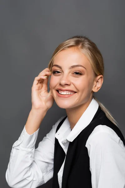 Cheerful blonde businesswoman looking at camera on grey background — Stock Photo