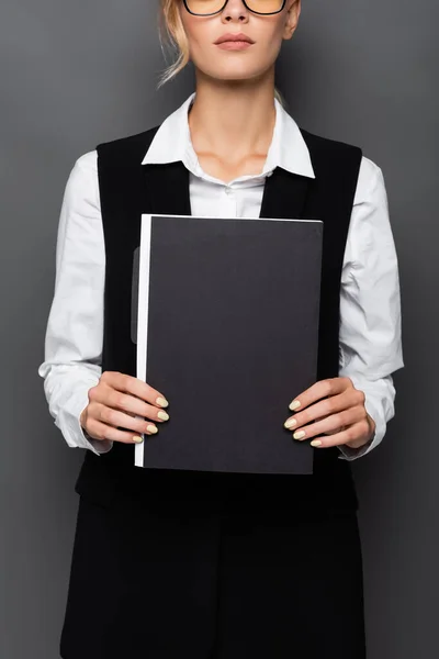 Обрізаний вид молодої бізнес-леді в окулярах, що тримає паперову теку ізольовано на сірому — стокове фото