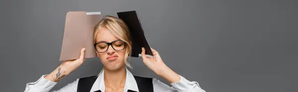 Tired businesswoman holding paper folders isolated on grey, banner — Stock Photo