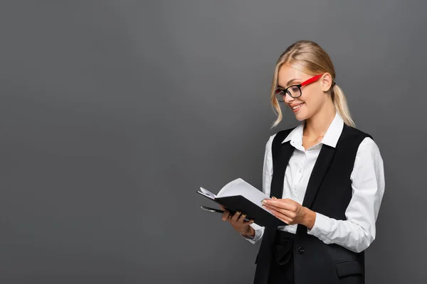 Lächelnde Geschäftsfrau hält Stift und Notizbuch isoliert auf grau — Stockfoto