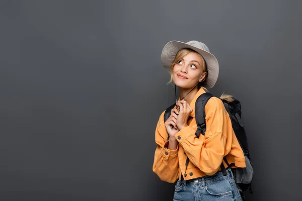 Dreamy traveler with backpack looking away isolated on grey — Stock Photo