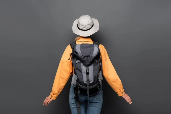 Vista trasera del turista con la mochila de pie sobre fondo gris - foto de stock