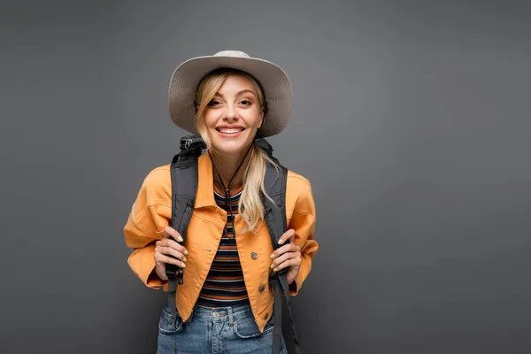 Красивая блондинка турист с рюкзаком глядя на камеру изолированы на серый — стоковое фото