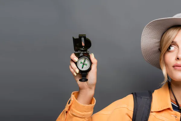 Обрізаний вид молодого туриста в капелюсі тримає компас ізольовано на сірому — стокове фото