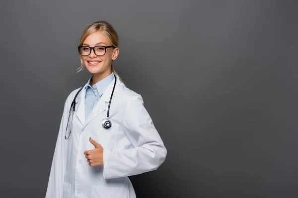 Позитивний лікар в окулярах показує, як жест ізольований на сірому — стокове фото
