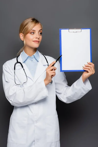 Молодий лікар вказує в кишені з копіювальним простором ізольовано на сірому — стокове фото