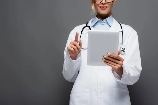 Vista recortada de un joven médico de pelaje blanco con un comprimido digital aislado en gris - foto de stock