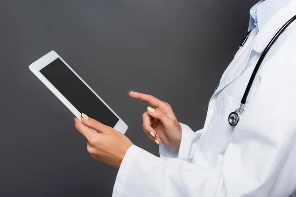 Обрезанный вид врача, держащего цифровой планшет с чистым экраном, изолированным на сером — стоковое фото