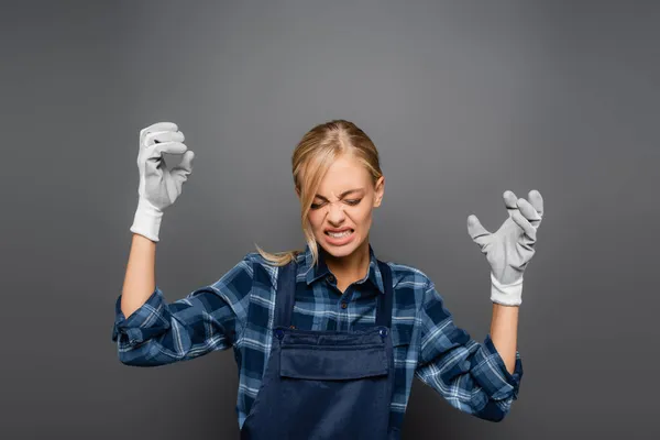 Plomero agresivo en guantes de pie aislado en gris - foto de stock