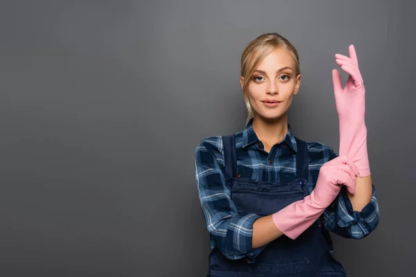 Junger Klempner trägt Gummihandschuhe isoliert auf grau — Stockfoto