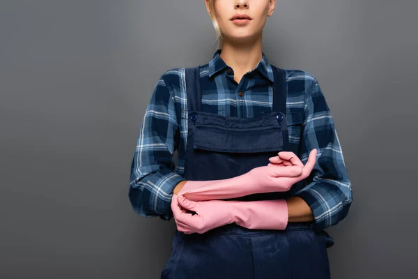 Vista recortada de la trabajadora con guantes de goma de pie aislados en gris - foto de stock