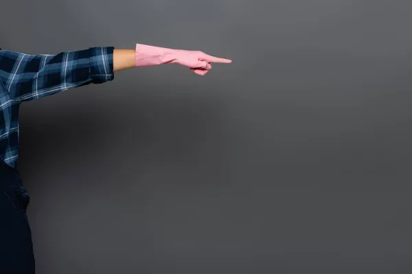 Cropped view of young plumber in rubber glove pointing with finger isolated on grey — Stock Photo