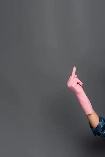 Обрізаний вид сантехніки в гумовій рукавичці, що показує жест середнього пальця на сірому — стокове фото