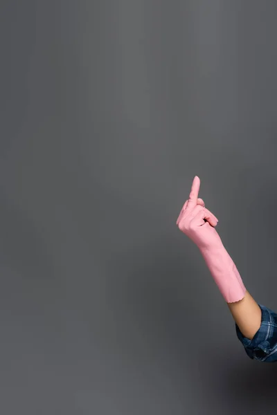 Cropped view of plumber in rubber glove showing middle finger gesture on grey — Stock Photo