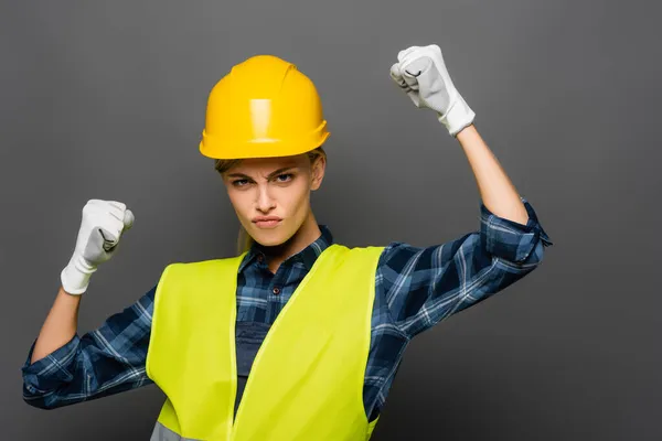 Serious builder in safety vest showing yes gesture isolated on grey — Stock Photo