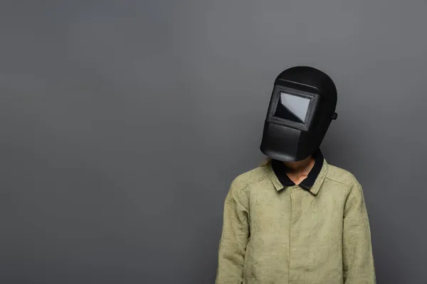 Soldador em uniforme protetor e máscara de pé isolado sobre cinza — Fotografia de Stock