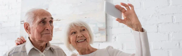 Personas mayores sonriendo mientras toman selfie en el hogar de ancianos, pancarta - foto de stock