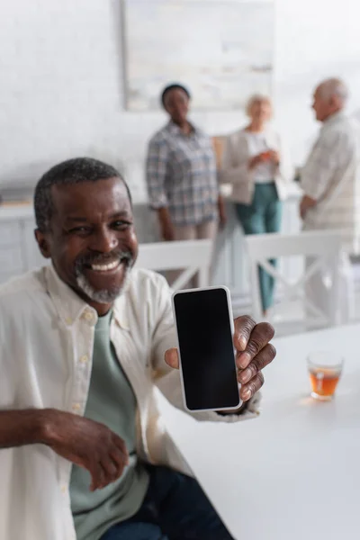 Smartphone in mano dell'uomo afroamericano sfocato nella casa di cura — Foto stock